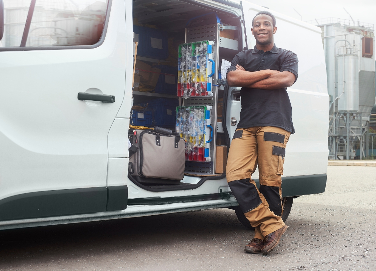 A tradesman leaning against his organised work van